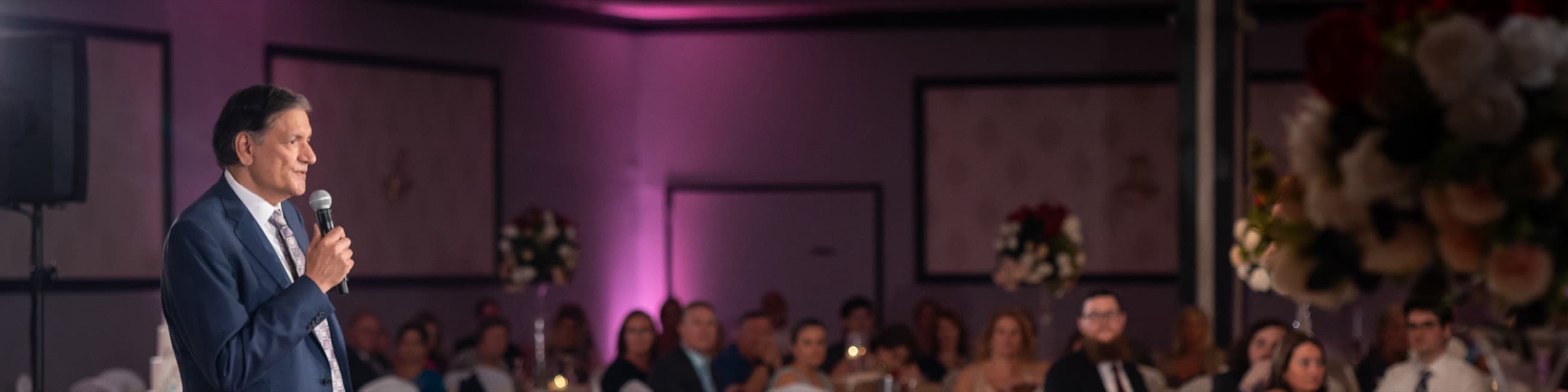 Shyam Dunna, Founder and Principal of nMomentum, speaking into a microphone before a seated audience